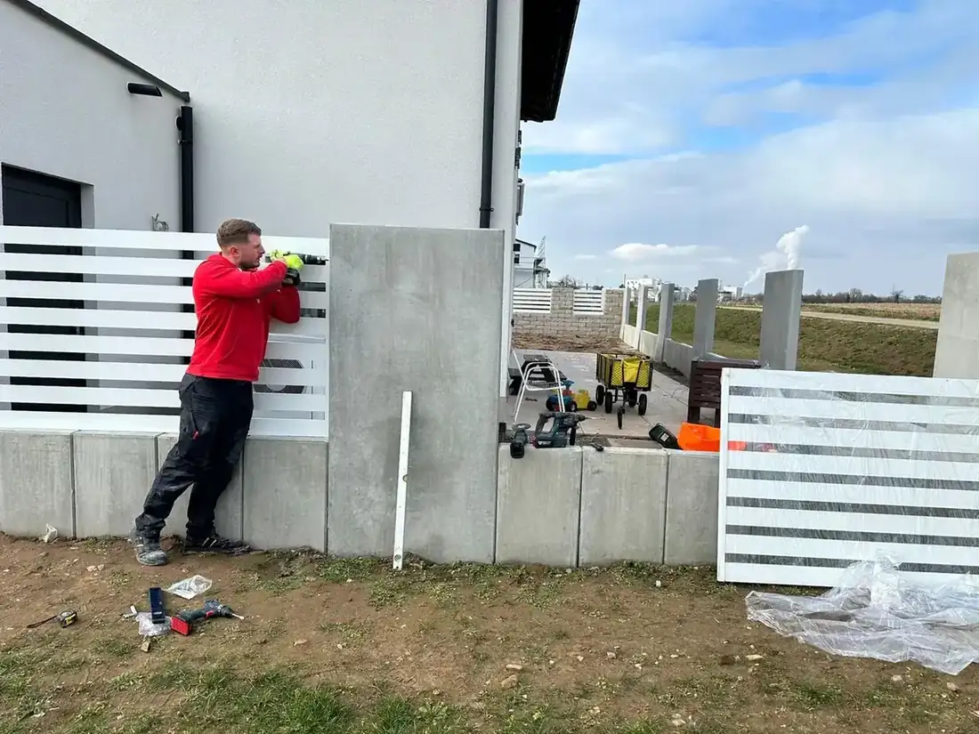 Montage eines weißen Lattenzauns auf Betonsockel